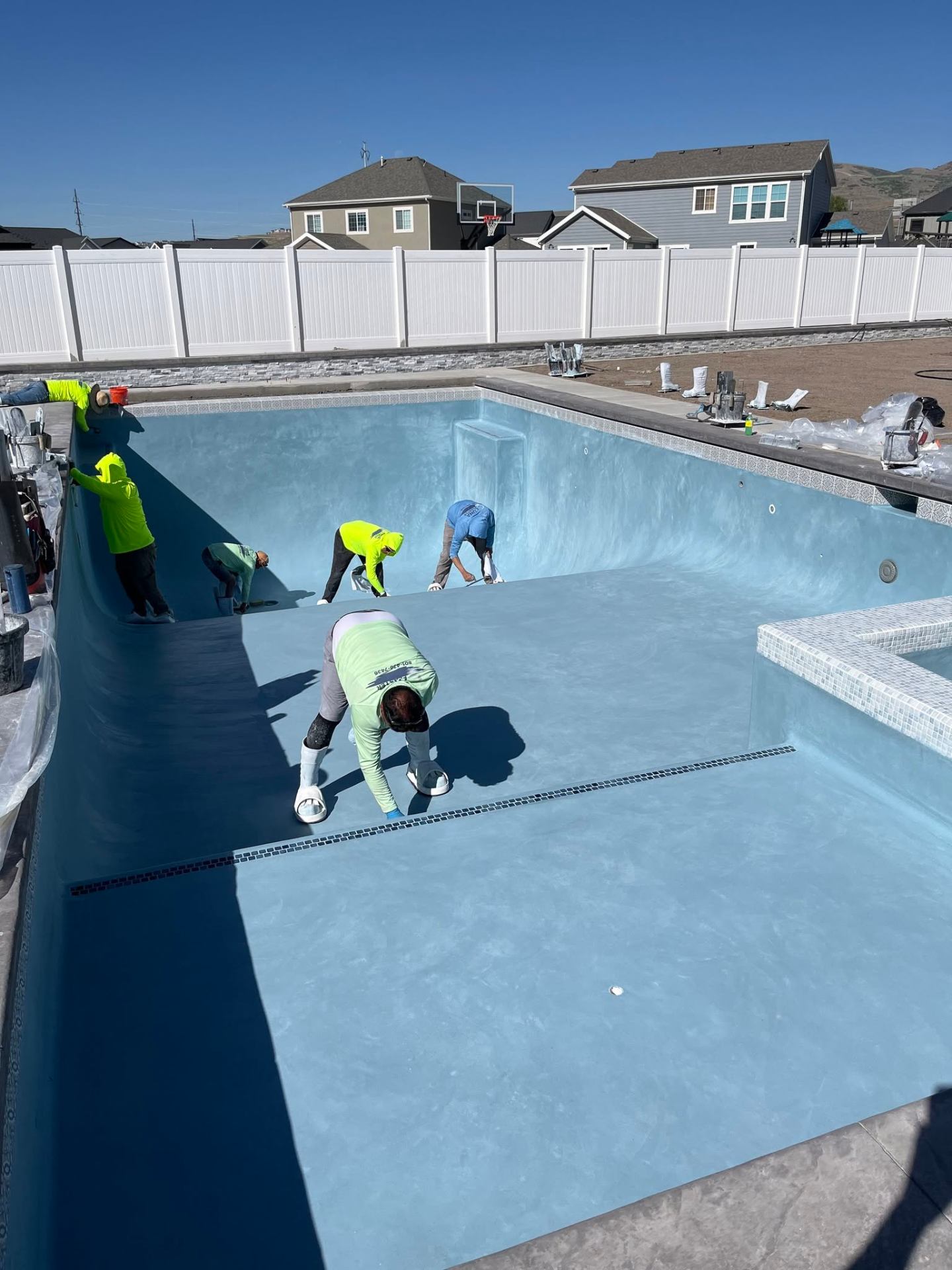 Crew troweling blue plaster interior finish inside an empty shotcrete pool shell