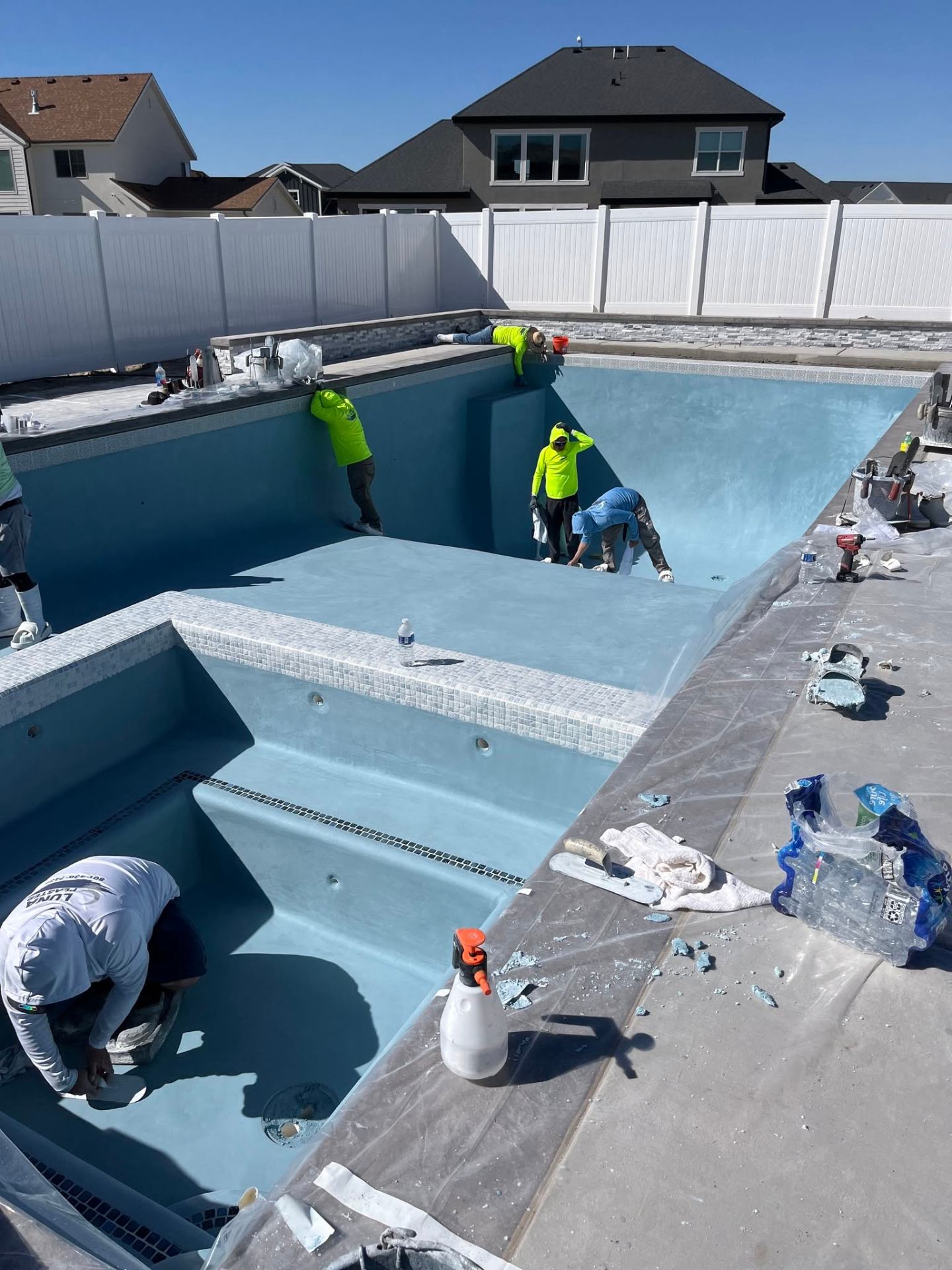 Fresh plaster being finished in a spa with white waterline tile and stone coping